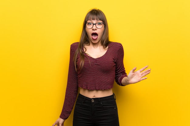 Femme, lunettes, mur jaune, expression faciale, choqué