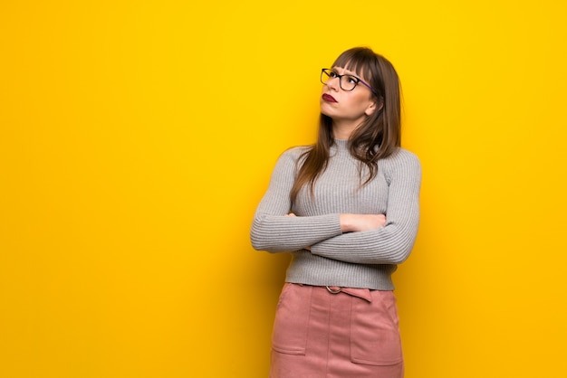 Femme, lunettes, mur jaune, levée, sérieux