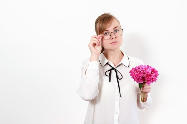 Une femme avec des lunettes avec des pivoines roses sur fond blanc