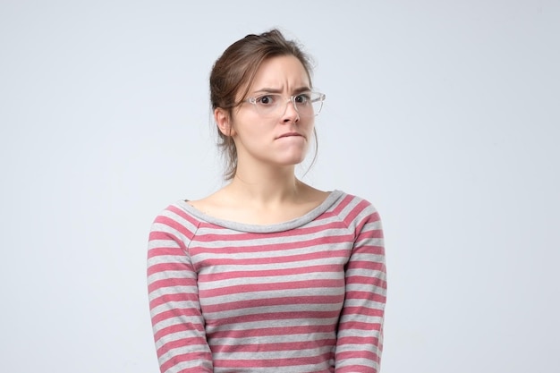 Femme à lunettes regarde de côté avec une expression pensive