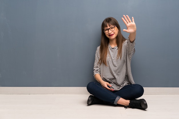 Femme, lunettes, séance, sol, saluer, à, main, heureux, expression