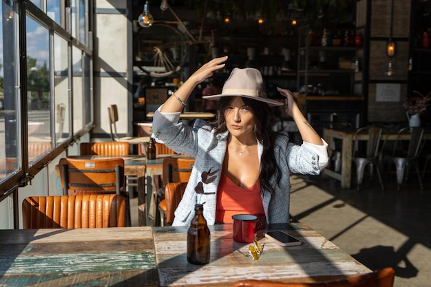 Femme avec des lunettes de soleil buvant une tasse de café tout en se relaxant dans un café