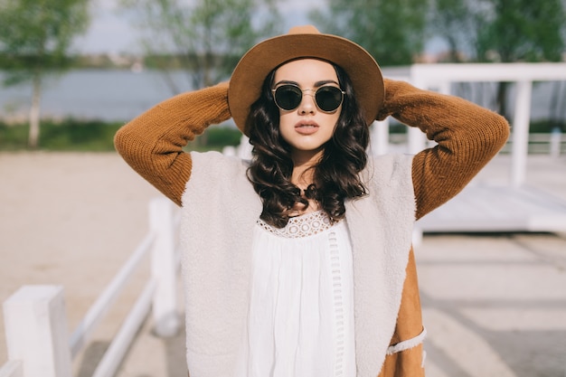 Femme à lunettes de soleil en gardant les mains derrière la tête