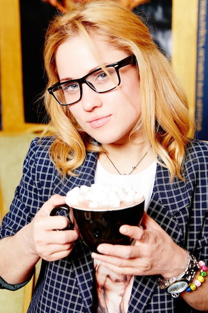 Une femme avec des lunettes et une tasse de café
