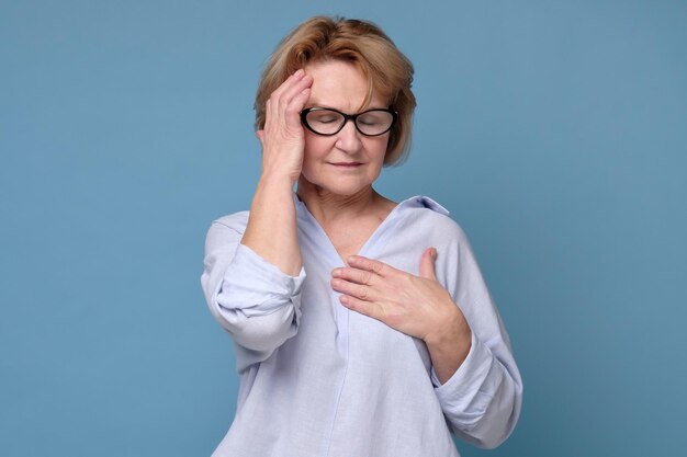 Femme à lunettes tenant la main sur son front souffrant de migraine ou de mal de tête