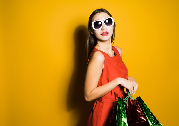 Une femme avec des lunettes tient des sacs à provisions