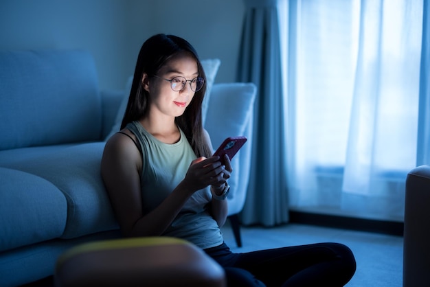 Femme avec des lunettes et l'utilisation du téléphone portable le soir à la maison