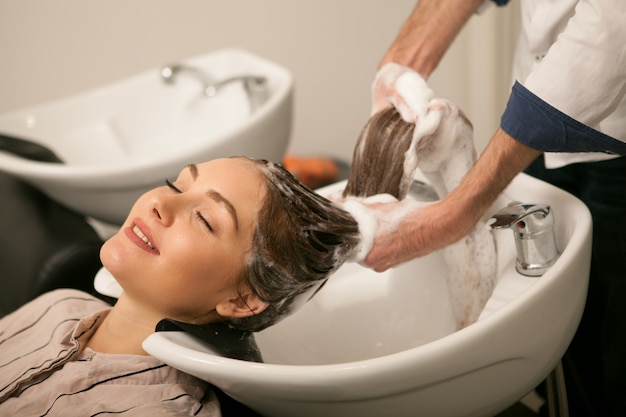 Une femme magnifique se fait laver les cheveux par un coiffeur.