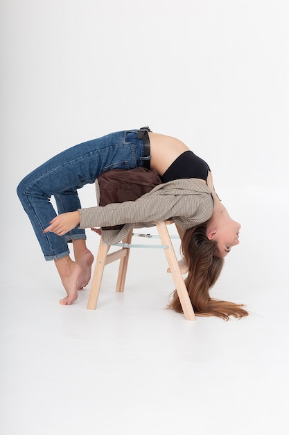 Femme maigre allongée en position de pont sur une échelle en bois au studio avec les pieds nus