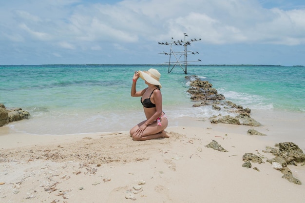 Photo femme en maillot de bain assis sur la plage ensoleillée avec la mer des caraïbes colombienne en arrière-plan