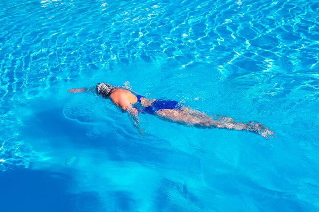 Femme avec maillot de bain nageant sur une piscine d'eau bleue.