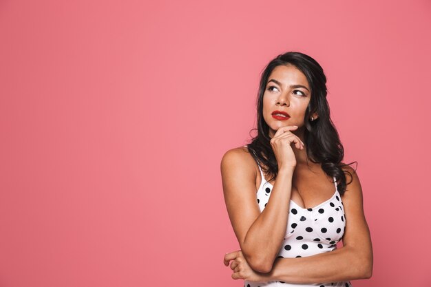 Femme en maillot de bain posant isolé sur mur rose à côté.