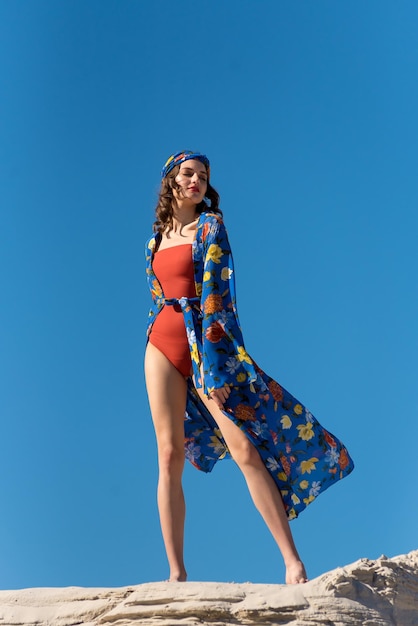 Une femme en maillot de bain rouge avec un imprimé de fleurs bleues et jaunes dessus.