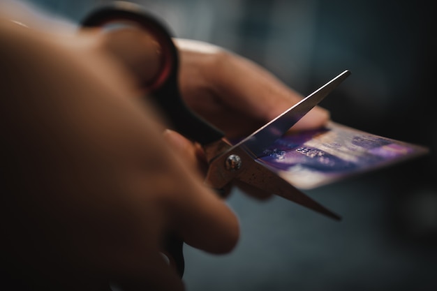 Femme main coupant la carte de crédit en or avec des ciseaux.