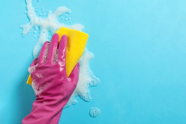 Femme main dans la main tenir l'éponge sur fond bleu avec de la mousse