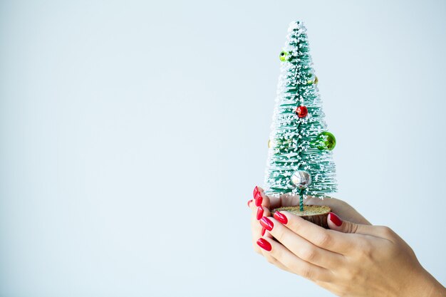 Femme à la main avec des décorations de Noël sur fond gris