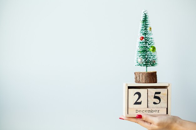 Femme à la main avec des décorations de Noël sur fond gris