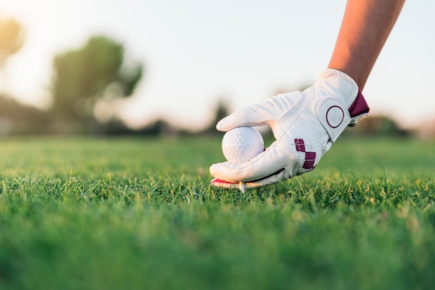 Femme de main mettant une balle de golf sur le tee. Concept de golf.