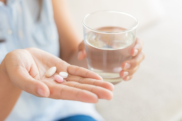 Femme main avec pilules comprimés de médecine et verre d&#39;eau pour le traitement des maux de tête