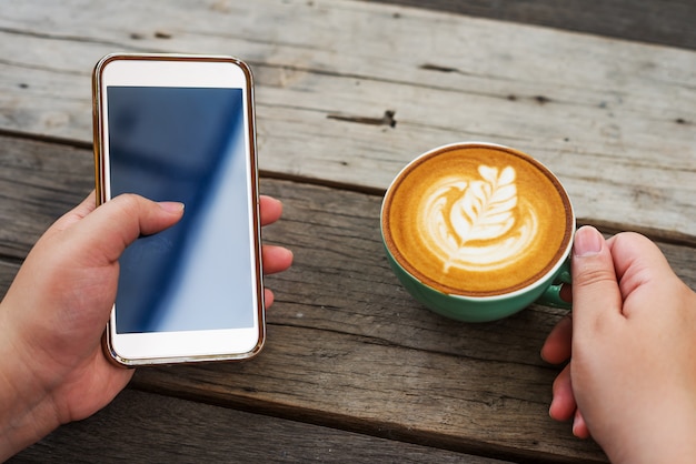 Femme à la main avec smartphone mobile et café cappuccino