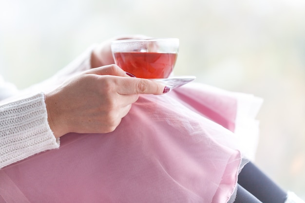 Femme main tasse de thé en fond de fenêtre