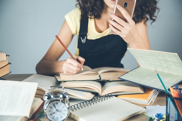 Femme main téléphone intelligent avec des livres sur le bureau