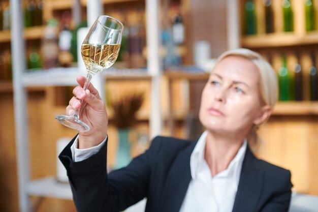 Femme main tenant bokal avec vin blanc tout en examinant sa couleur et d'autres caractéristiques