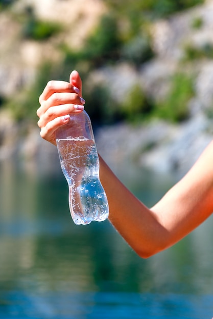 Femme main tenant une bouteille d'eau minérale à l'extérieur