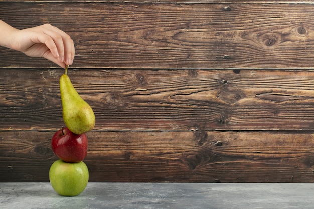 Femme main tenant poire verte sur table en marbre.