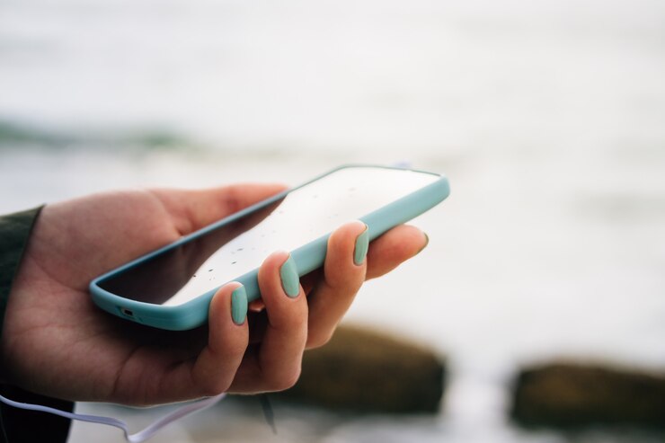 Photo femme main tenant un téléphone portable contre la mer