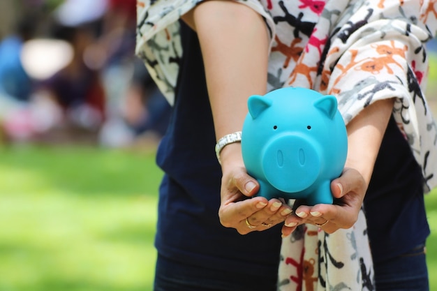 Photo femme main tenant une tirelire bleue, idées d'investissement financier ou bancaire