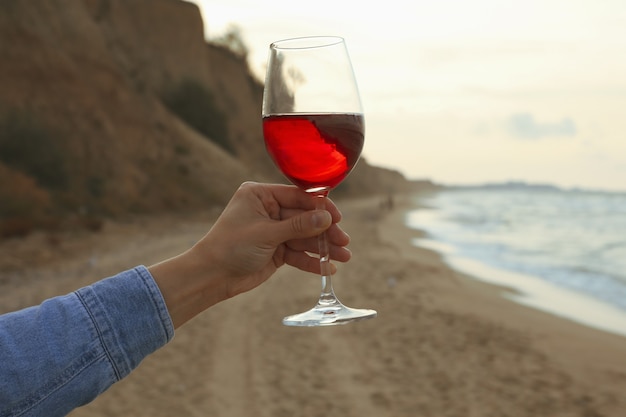 Femme main tenant un verre de vin sur la plage de sable