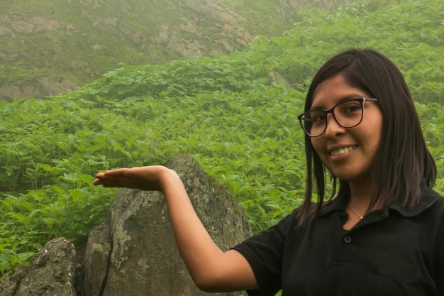 Femme avec la main tendue au milieu d'un paysage vert et nuageux