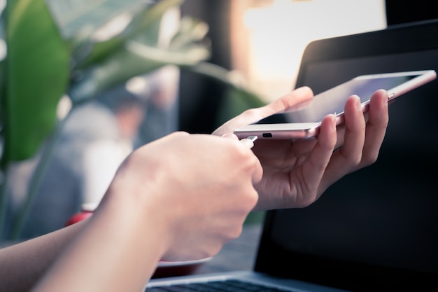 Femme main tenir le câble de charge en branchant le téléphone mobile intelligent