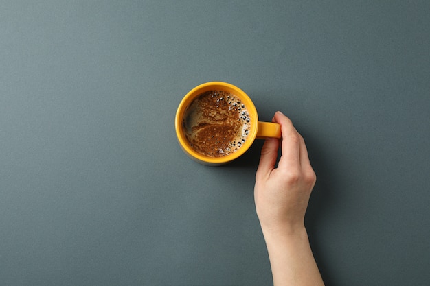 Femme main tenir la tasse de café avec de la mousse mousseuse sur fond noir