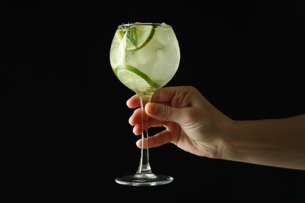 Femme main tenir le verre de cocktail aux agrumes sur fond sombre