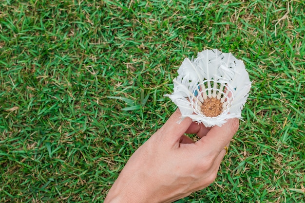 Femme main tenir le volant, balle de badminton sur fond d&#39;herbe verte