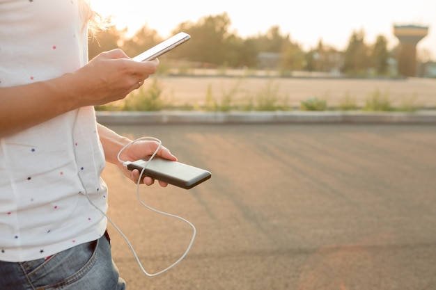 Femme mains tenant un smartphone noir chargeant la batterie de la banque d'alimentation externe