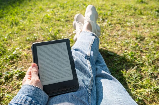 Femme mains vue pov tenant un livre électronique lecture à l'extérieur