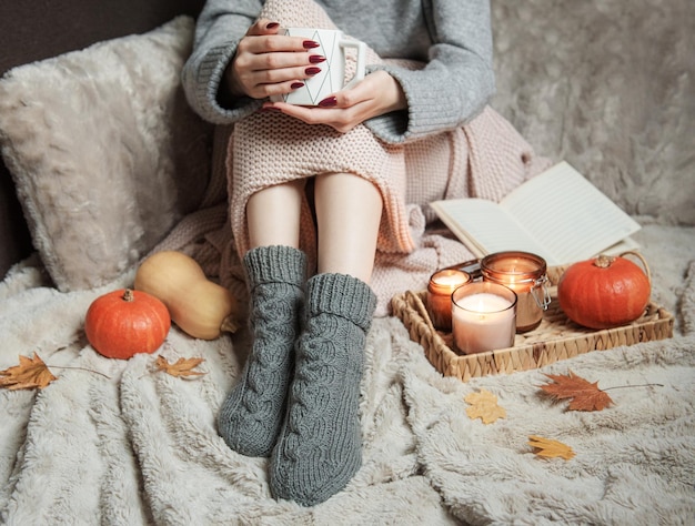 Une femme à la maison confortable recouverte d'une couverture chaude boit du café