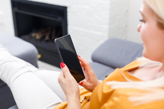 Femme à la maison se détendre sur un canapé-lit en lisant des e-mails sur la connexion wifi de l'ordinateur tablette