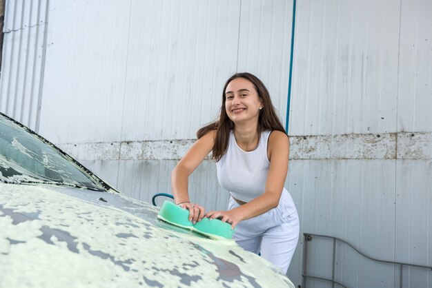 Femme Maître à L'aide D'une éponge Verte En Mousse Blanche Pour Nettoyer Son Auto De La Saleté