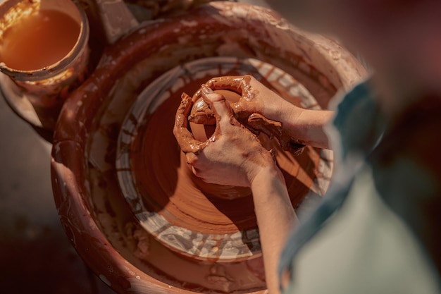 Femme maître façonner l'argile sur le tour de potier en atelier