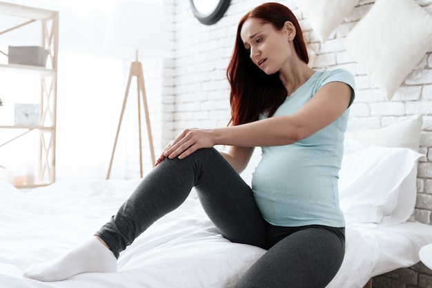 Une femme a mal au genou, elle fait un massage.