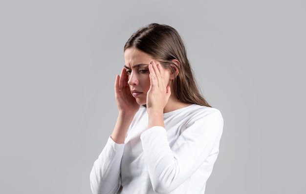 Femme avec mal de tête dur tenant les mains sur la tête Femme brune touchant ses tempes se sentant stressée sur fond gris Femme souffrant de maux de tête désespérément stressé parce que la douleur et la migraine