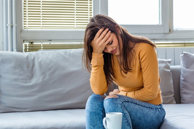 Femme avec un mal de ventre assis sur le canapé