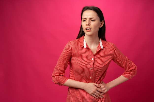 Femme malade ayant mal au ventre sur fond rose