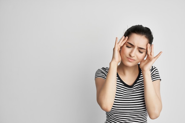 Femme malade dans un tshirt rayé douleur dans le fond clair du cou