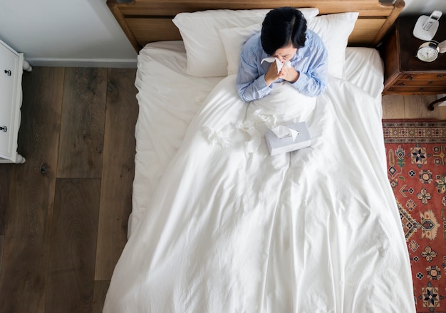 Femme malade sur le lit se moucher