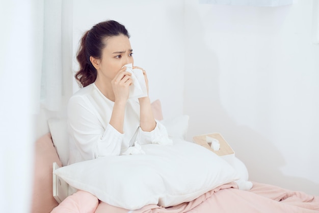 Femme malade avec mal de tête assis sous la couverture